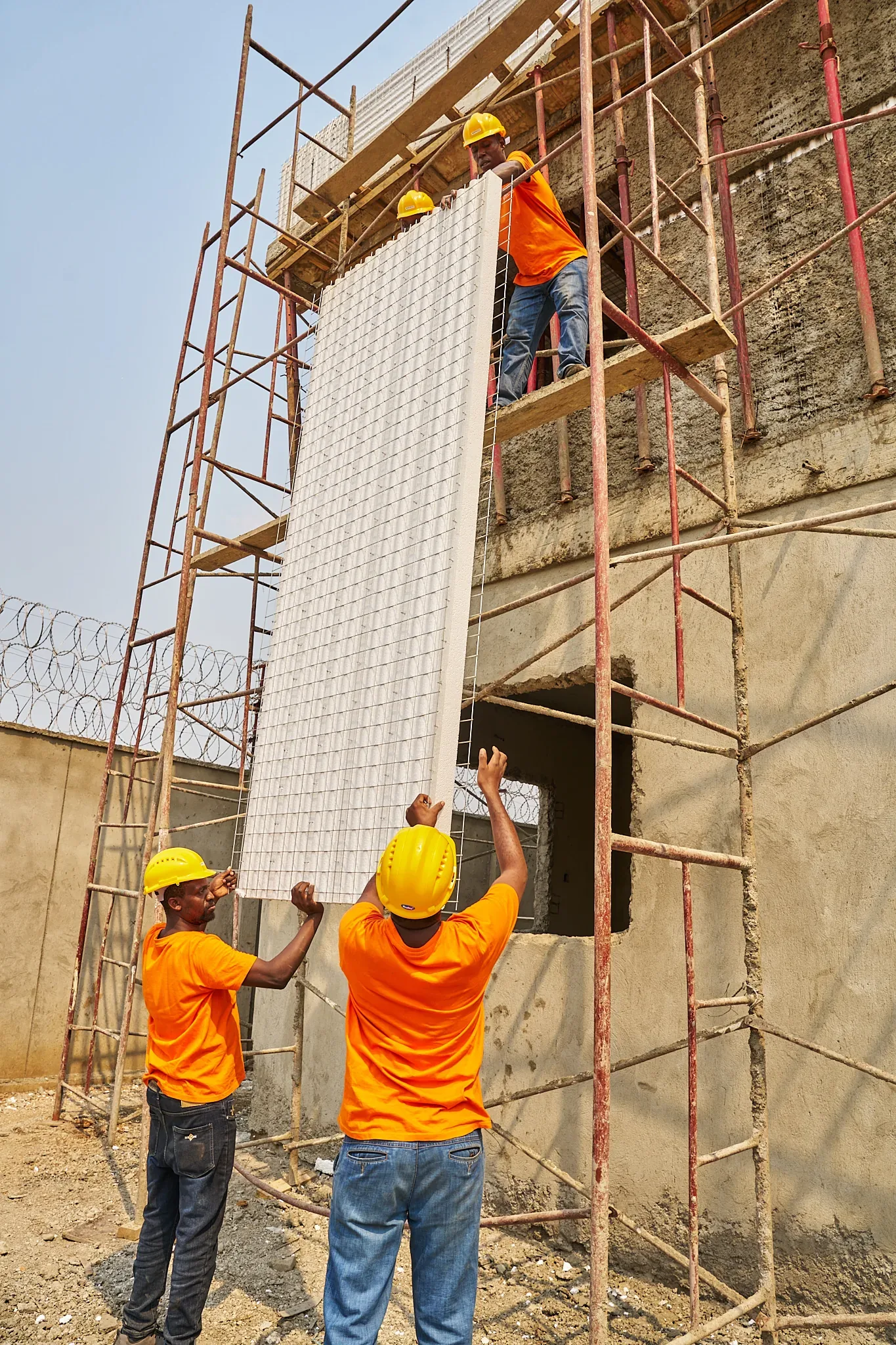 SPECO crew lifting an EPS wall panel into position on site in Juba
